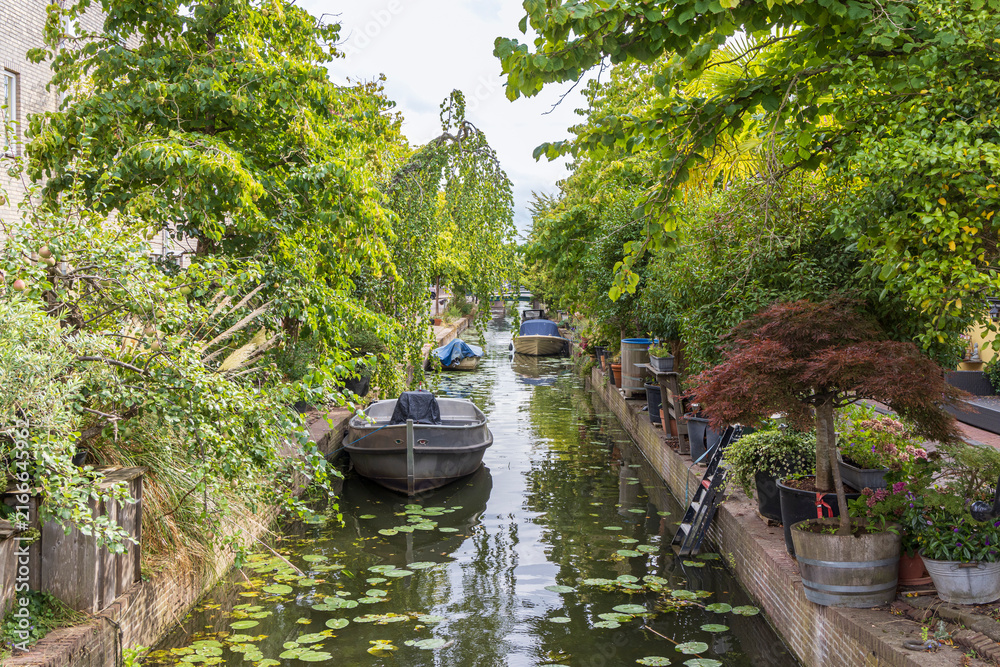Obraz premium Canal boats and lush garden terraces along a narrow residential waterway in Leiden, The Netherlands