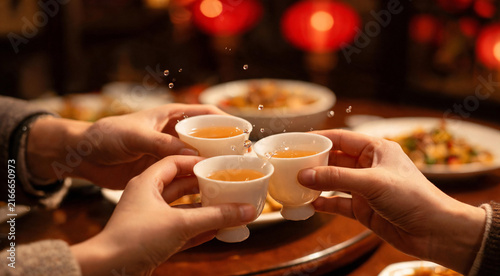 Family hands toasting with small wine glasses at Chinese New Year dinner