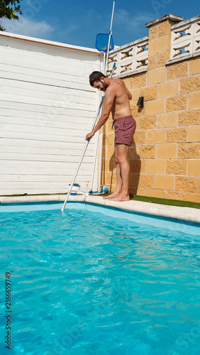 Man clean pool during relaxed summer vacation at home