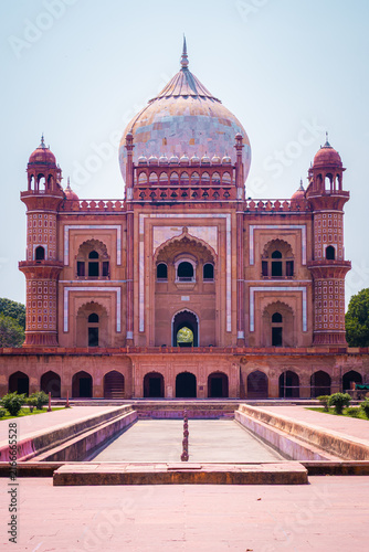 Photography Front view of Safdarjung Tomb with its grand central dome and symmetrical Mughal facade reflected by the empty water channel in New Delhi, India
