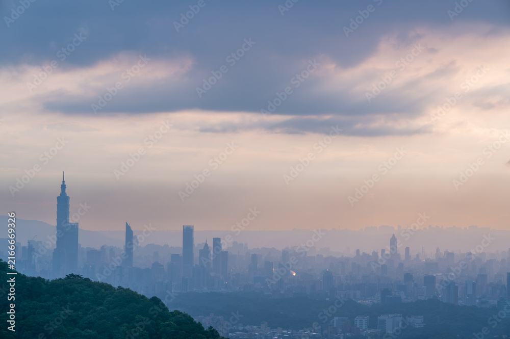 Obraz premium Panoramic view of the Taipei city skyline and Taipei 101 tower viewed from Mount Datian in New Taipei, Taiwan, during a hazy sunset.