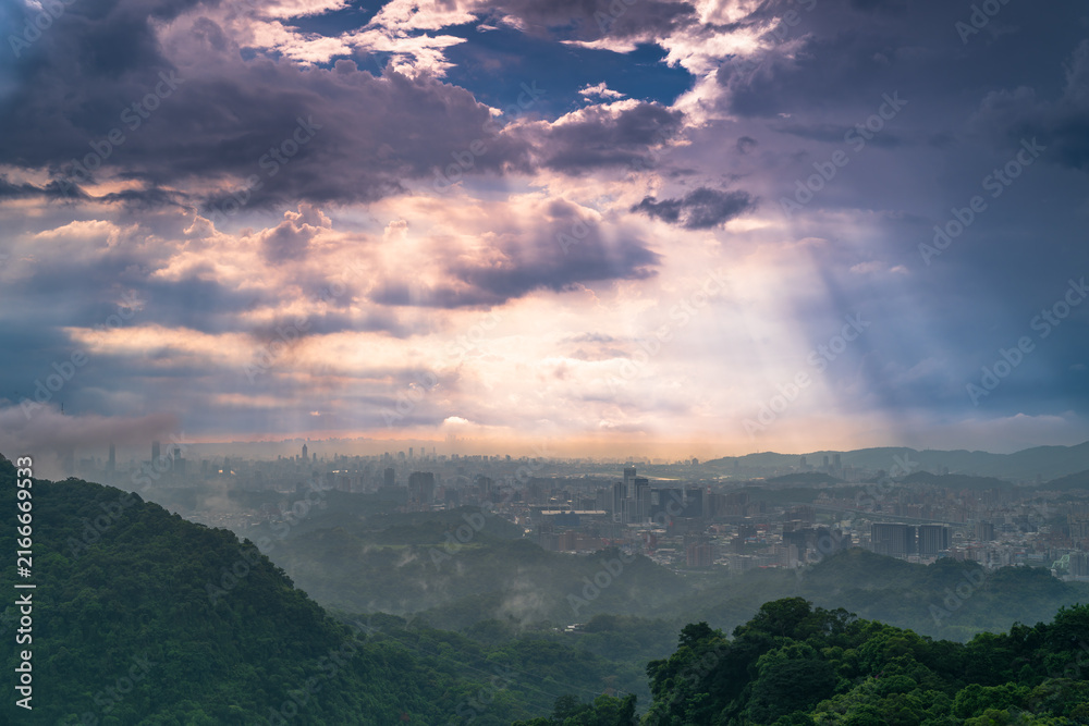 Naklejka premium Stunning aerial view of Taipei city skyline and mountain landscape with dramatic clouds and sun rays during sunset in Taiwan.