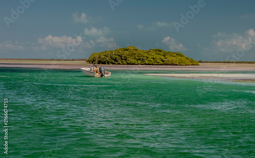 Quadro su tela A small tropical island and a small boat surrounded by ocean and blue sky