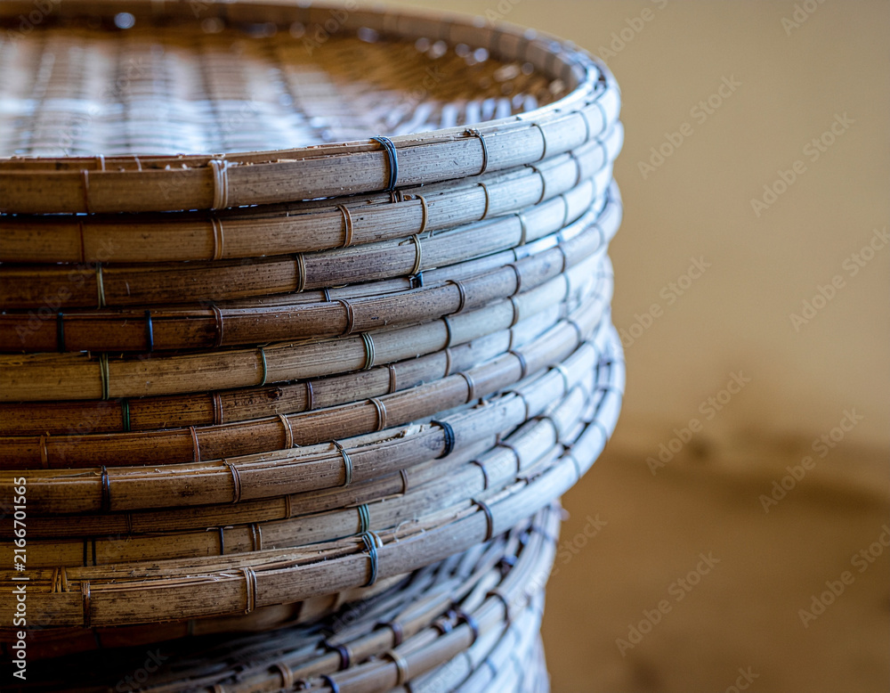 Obraz premium close up view of a neat stack of traditional handcrafted woven bamboo winnowing trays, showing stitched circular cane rims and rustic woven texture