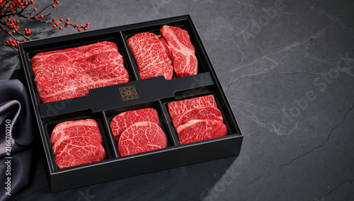 Premium Korean Hanwoo beef gift box with fresh raw meat cuts arranged for Chuseok holiday celebration on a dark stone background.