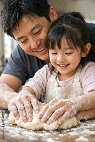Father and daughter baking bread together with flour covered hands for family cooking activity and parenting poster