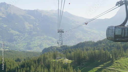 Scenic view from a gondola lift travelling over a green alpine valley and forest. Switzerland