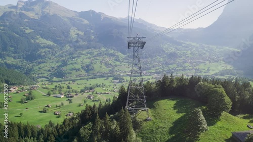 Point of view from a cable car traveling up a mountain, overlooking a verdant alpine valley. Switzerland