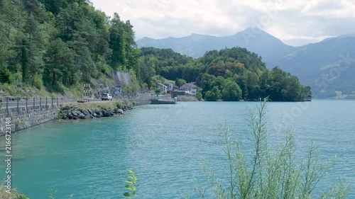 Beautiful mountain lake with turquoise water and a scenic road carved into the lush green hillside. Switzerland