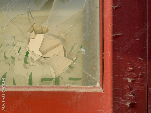 Foto Broken window on an old weathered red door with pealing paint