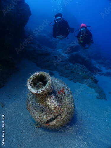 scuba divers are exploring antic old amphoras underwater