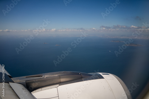 Photography View of passenger airplane jet engine through illuminator flying above blue sea water