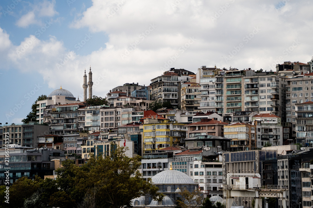 Fototapeta premium Wide view of dense residential buildings and mosque minarets located on a hill in Istanbul. Classic urban turkish landscape representing travel destination and oriental architecture concept.
