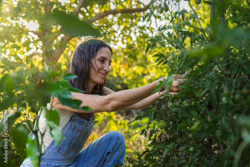 Woman smiles as she reaches for green leaves