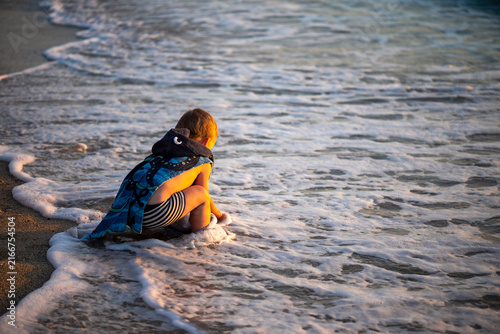 Child enjoying in gentle waves during summer vacation on exotic tropical beach.