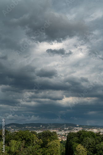 Dramatic dark storm clouds over city landscape and green hills in Vienna
