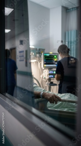 Hospital Intensive Care Unit With Patient And Medical Equipment Visible Through Glass Window