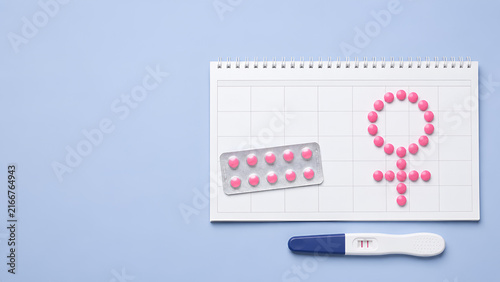 Pregnancy test and pills form female symbol for fertility reproductive health treatment and family planning on calendar.