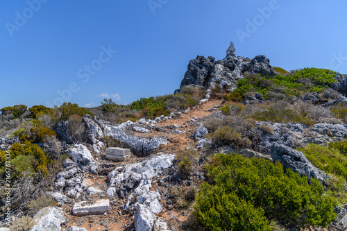 Konstfotografi Stony path climbing through low scrub to a tiny whitewashed chapel on a rocky su