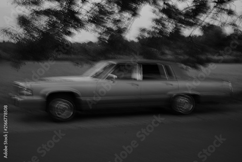 Obraz na plátně An artistic black and white fine art photograph featuring intentional camera movement (ICM) and motion blur of a classic vintage luxury sedan