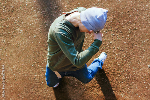 Foto High-angle shot of a stylish breakdancer in a beanie kneeling on an outdoor court