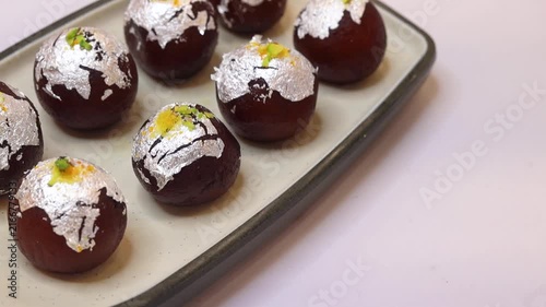 Kala jam or gulab jamun garnished and served on a white fancy plate