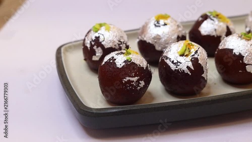 Kala jam or gulab jamun garnished and served on a white fancy plate