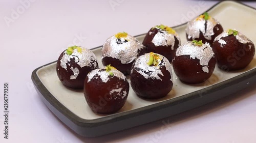 Kala jam or gulab jamun garnished and served on a white fancy plate