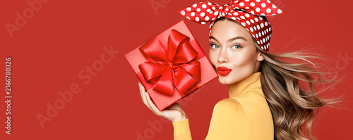 Beautiful fashionable cheerful young woman with a gift box