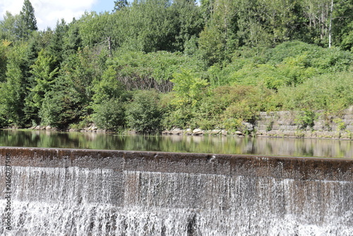 Dam in the mountain. Panorama of a picturesque landscape in summer and St-Charles in Quebec city. Beautiful river with trees reflections and waterfalls. Protection of the water and environment.