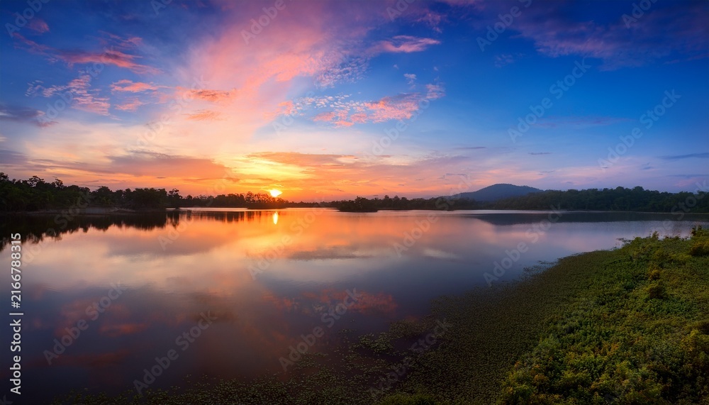Fototapeta premium Background Image Of The Reservoir Beautiful Sunrise Or Sunset Sky Over Calm Lake With Reflection In Surface Water In The Morning Or Evening Copy Space Lam Taphen Reservoir Suphanburi