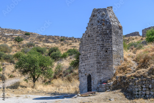 Tall gabled stone tower with a pointed arched doorway inside the fortress of Acrocorinth, Greece