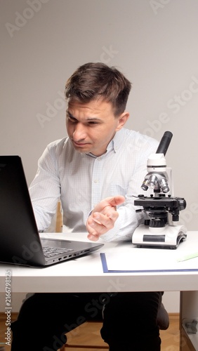 Fotografie male scientist focused on his laptop screen, actively conducting research and da