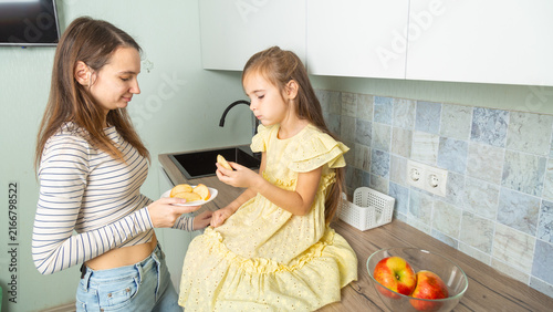 Happy day! Mom and her daughter child girl are playing, smiling, eating fruit in the kitchen. Family holiday and togetherness.