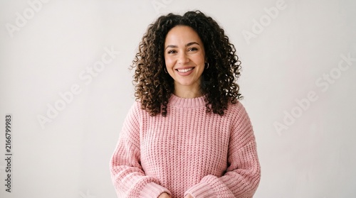 Young woman with curly hair smiling in a pink sweater