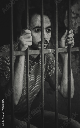 Young man behind metal bars in black and white