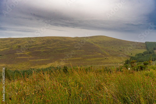 Rolling hills stretch under a moody, cloudy sky
