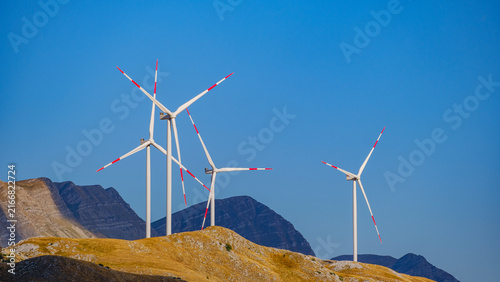Multiple wind turbines across a mountain landscape, representing renewable energy, clean technology, sustainable development and the transition toward a low-carbon future.