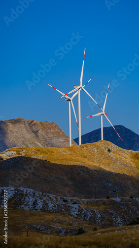 Multiple wind turbines across a mountain landscape, representing renewable energy, clean technology, sustainable development and the transition toward a low-carbon future.