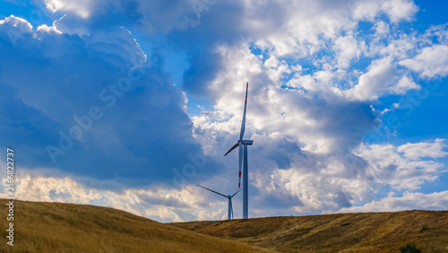 Multiple wind turbines across a mountain landscape, representing renewable energy, clean technology, sustainable development and the transition toward a low-carbon future.