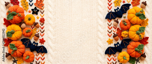 A cozy knitted autumn Halloween banner mockup with a blank copy space for text, framed by cute handmade knitted orange pumpkins, bats, embroidered leaves on a creamy white cable-knit background