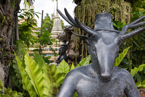Quadro su tela Das Bild zeigt eine dunkle Metallstatue eines anthropomorphen Wesens mit einem Hirschkopf und einem Geweih im Tempelgarten des Wat Pho in Bangkok