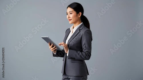 Professional Woman with Tablet: A focused businesswoman in a sharp suit stands confidently, engaging with a digital tablet.