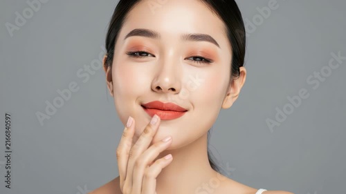 Asian Woman with Makeup: A beautiful Asian woman with flawless skin, styled hair, and elegant makeup touches her lips, showcasing a radiant and sophisticated look.