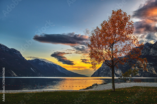 Scenic View of Lake Garda at Sunset with Golden Autumn Foliage and Mountain Silhouettes