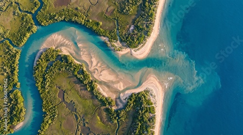Aerial top down view of curving river meeting turquoise sea and beach