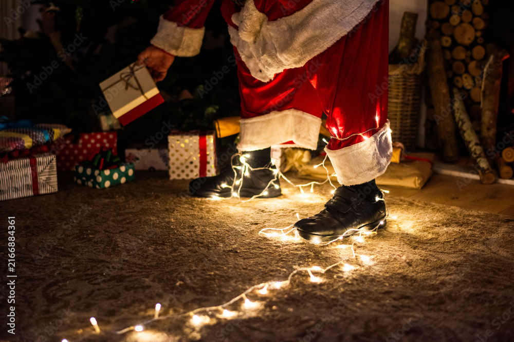 Obraz premium Santa placing gift under tree.