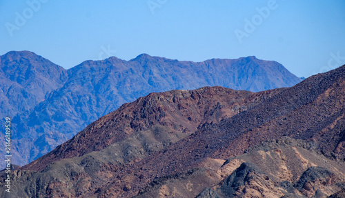 Картината върху платно Layered mountain ridges receding into the distance under a bright blue sky