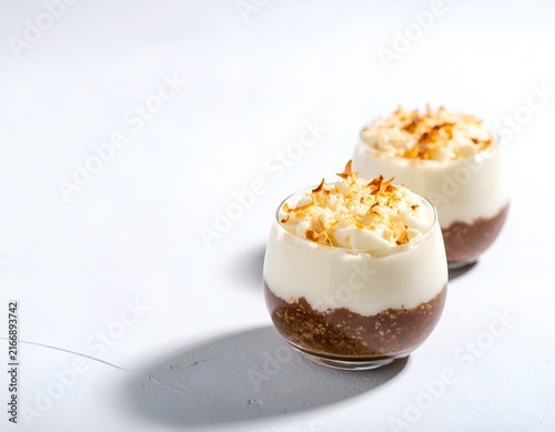 Two coconut pudding glasses on white background.