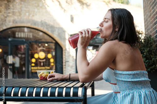Sticker Woman drinking healthy smoothie and eating fruit salad outdoors